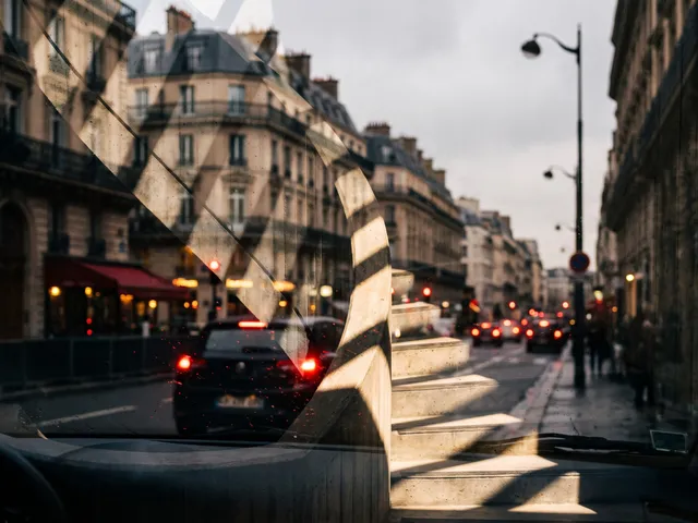 Rue parisienne vue depuis l’habitacle d’une voiture, immeubles haussmanniens et feux arrière rouges des véhicules dans la circulation